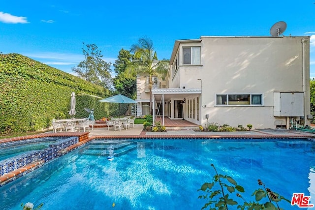 back of house with a swimming pool with hot tub and a patio