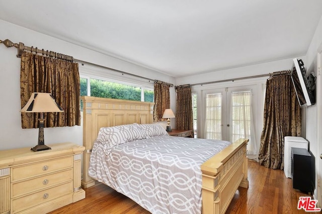 bedroom with french doors, access to exterior, hardwood / wood-style floors, and multiple windows