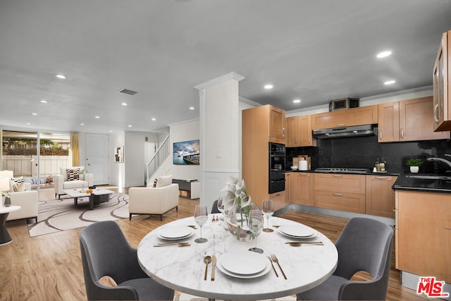 dining space with crown molding, sink, and light wood-type flooring