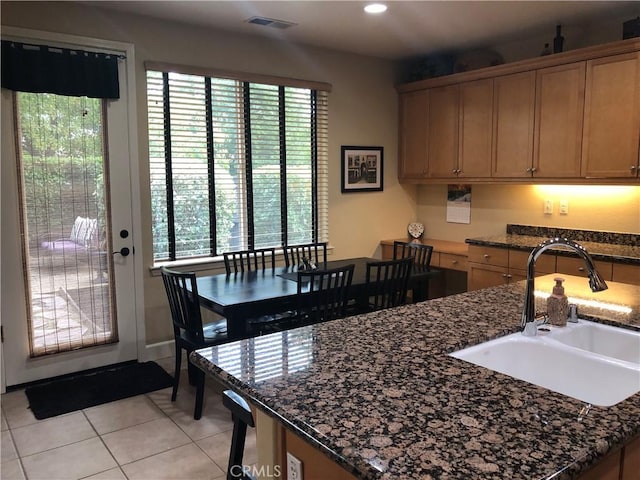 kitchen featuring dark stone countertops, sink, and light tile patterned floors