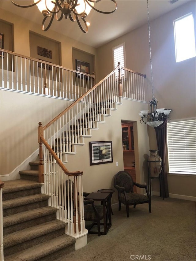 stairway with a chandelier, a towering ceiling, and carpet flooring