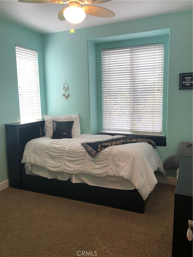 bedroom with ceiling fan, carpet floors, and multiple windows