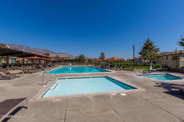 view of swimming pool with a mountain view, a patio area, and a community hot tub