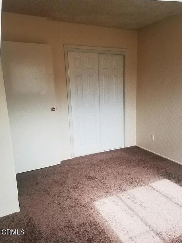 unfurnished bedroom with carpet, a textured ceiling, and a closet