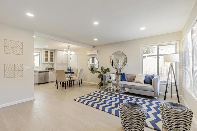 living room with an AC wall unit, an inviting chandelier, and light hardwood / wood-style floors