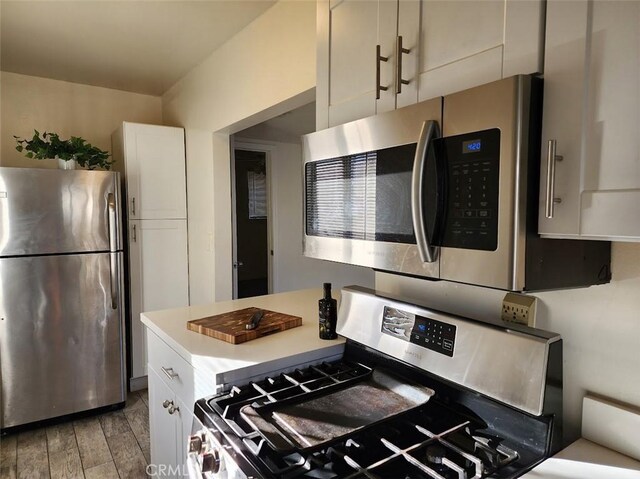 kitchen featuring appliances with stainless steel finishes, light wood-type flooring, light countertops, and white cabinetry