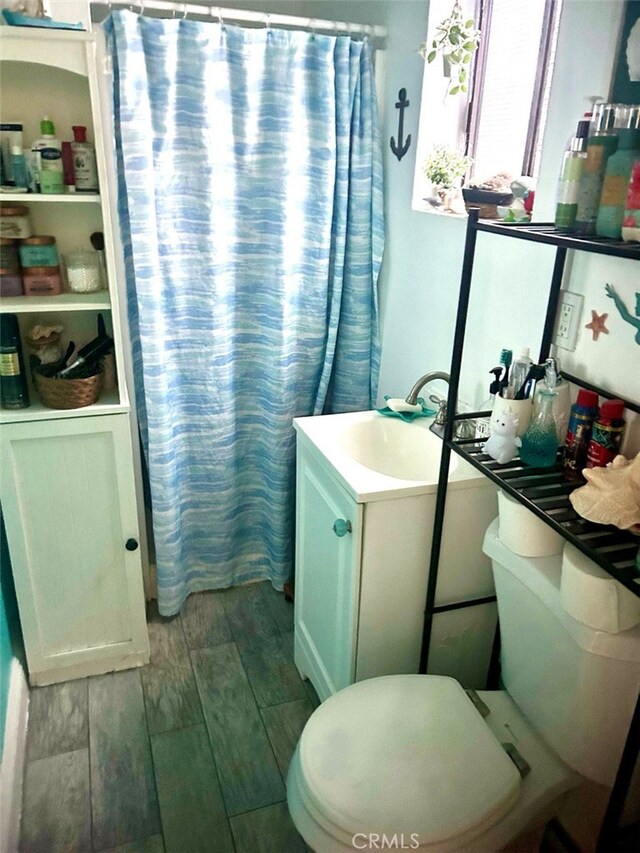 full bathroom featuring toilet, curtained shower, vanity, and wood finish floors