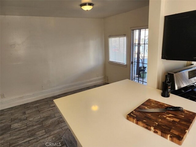 kitchen with dark wood-style floors, stainless steel range oven, baseboards, and light countertops