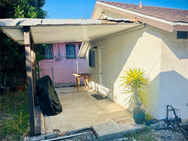 exterior space with roof with shingles, fence, a patio, and stucco siding