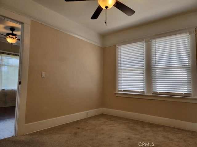 carpeted spare room featuring a ceiling fan and baseboards