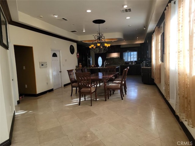 tiled dining area with an inviting chandelier, sink, and a raised ceiling