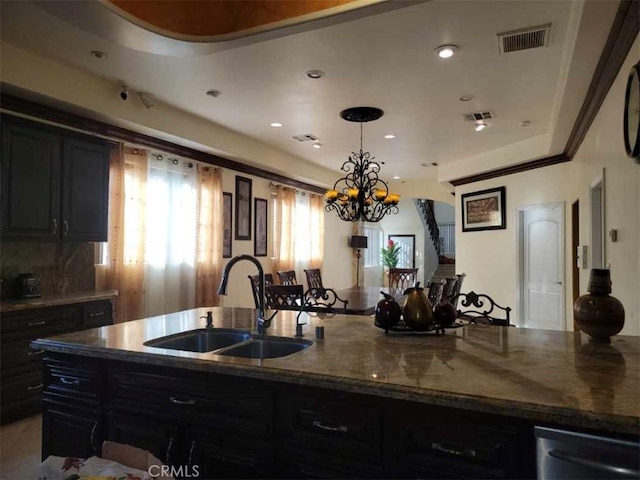 kitchen featuring sink, dark stone countertops, an inviting chandelier, and decorative light fixtures