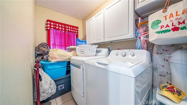 laundry area with washing machine and clothes dryer, light tile patterned flooring, and cabinets