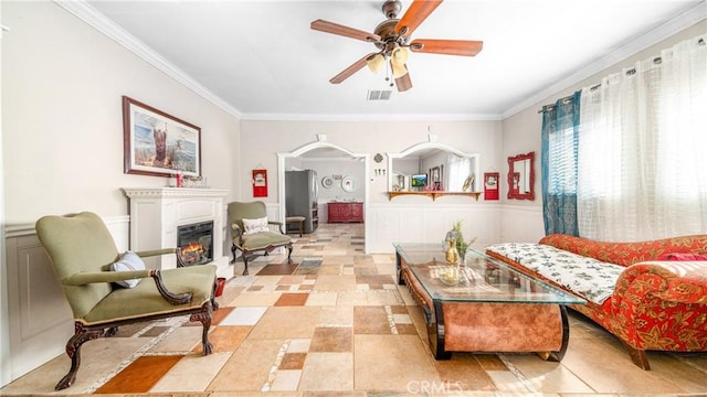 living area with ceiling fan and crown molding