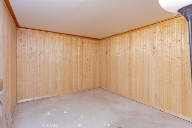 unfurnished room featuring wood walls and crown molding