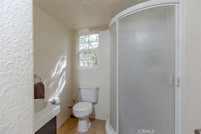 bathroom with hardwood / wood-style flooring, vanity, toilet, and walk in shower