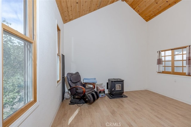 living area with high vaulted ceiling, light hardwood / wood-style floors, a wood stove, and wood ceiling