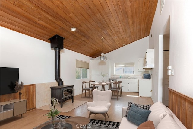 living room with a wood stove, high vaulted ceiling, wood ceiling, and light hardwood / wood-style floors