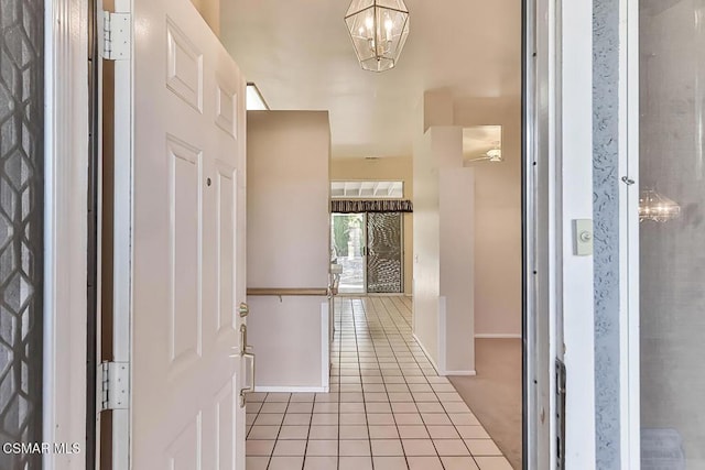 tiled entryway featuring a notable chandelier