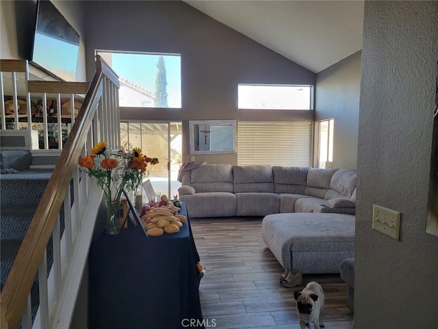 living room with a wealth of natural light, hardwood / wood-style floors, and high vaulted ceiling