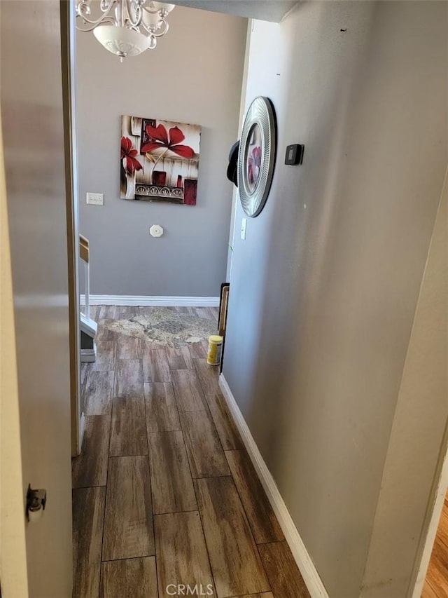 corridor with hardwood / wood-style floors and a chandelier