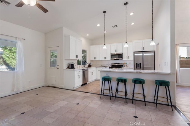 kitchen with white cabinets, sink, ceiling fan, appliances with stainless steel finishes, and a kitchen bar