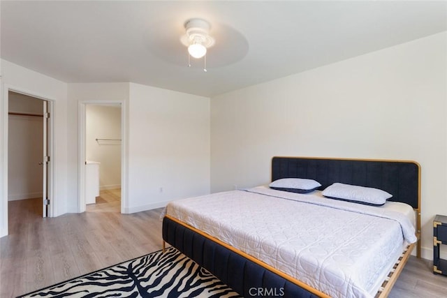 bedroom featuring ceiling fan, a closet, light hardwood / wood-style floors, and a spacious closet