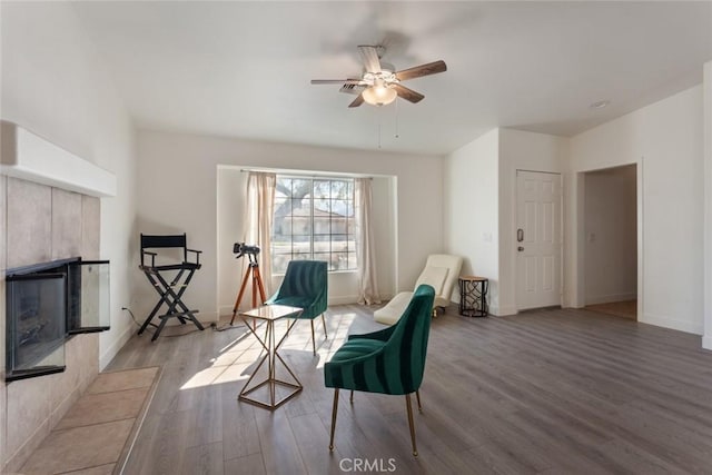 sitting room featuring ceiling fan, a fireplace, and light wood-type flooring