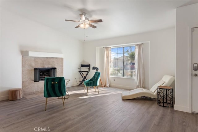 living area featuring hardwood / wood-style floors, ceiling fan, and a tile fireplace