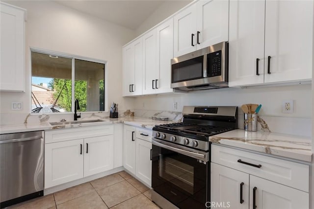 kitchen with white cabinets, sink, light tile patterned floors, appliances with stainless steel finishes, and light stone counters