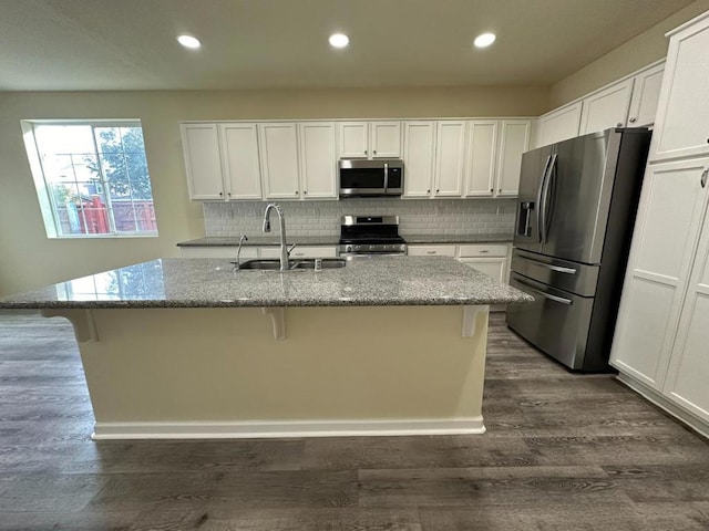 kitchen featuring appliances with stainless steel finishes, white cabinets, a center island with sink, and sink