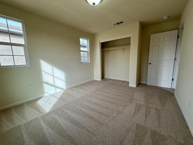 unfurnished bedroom with multiple windows, carpet, and a closet