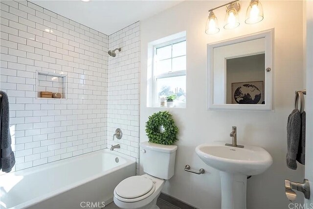 bathroom featuring tiled shower / bath combo and toilet