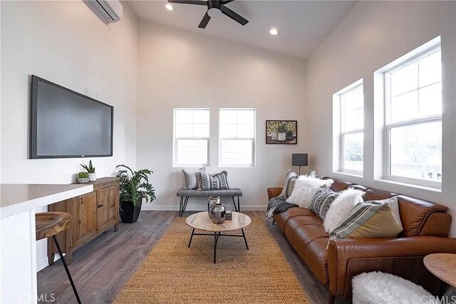 living room with dark hardwood / wood-style flooring, high vaulted ceiling, an AC wall unit, and ceiling fan