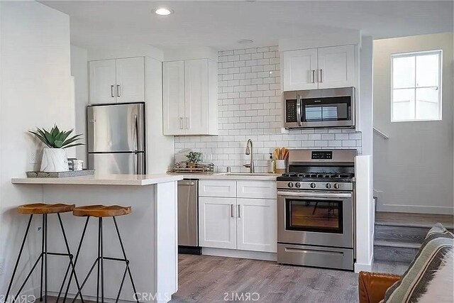 kitchen with white cabinets, a kitchen bar, sink, and appliances with stainless steel finishes