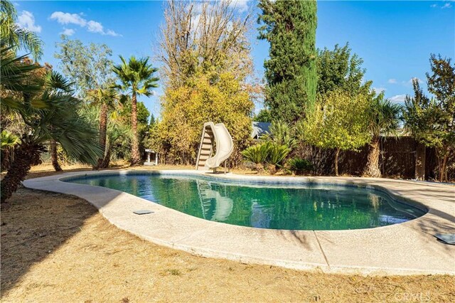 view of pool with a water slide and a fenced in pool