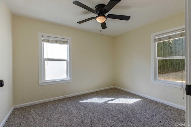 carpeted spare room featuring baseboards and a ceiling fan