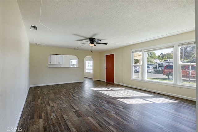 unfurnished living room featuring dark wood-style floors, arched walkways, visible vents, ceiling fan, and a textured ceiling