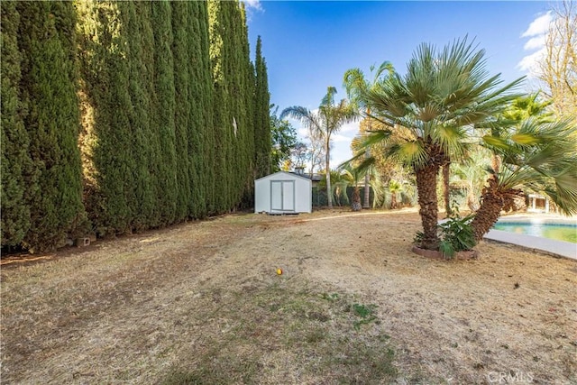 view of yard with a storage shed, an outdoor pool, and an outdoor structure