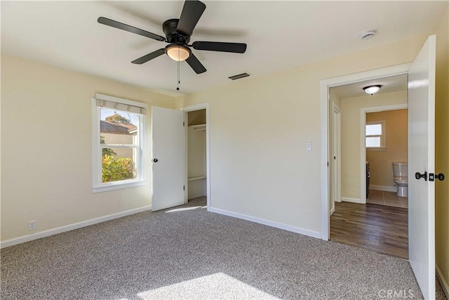 unfurnished bedroom featuring multiple windows, carpet, visible vents, and baseboards