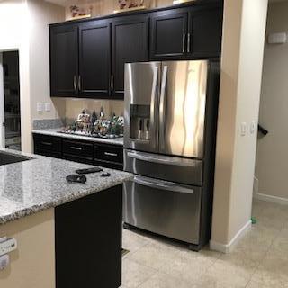 kitchen featuring light stone countertops, light tile patterned floors, and stainless steel fridge with ice dispenser