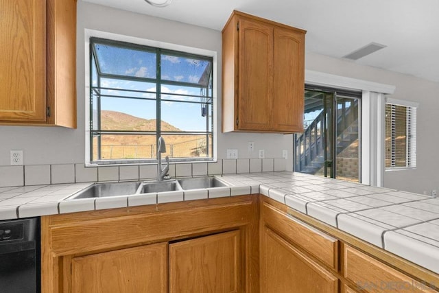 kitchen featuring a mountain view, black dishwasher, tile countertops, and a wealth of natural light