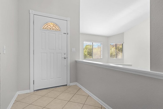 entryway featuring light tile patterned floors and vaulted ceiling