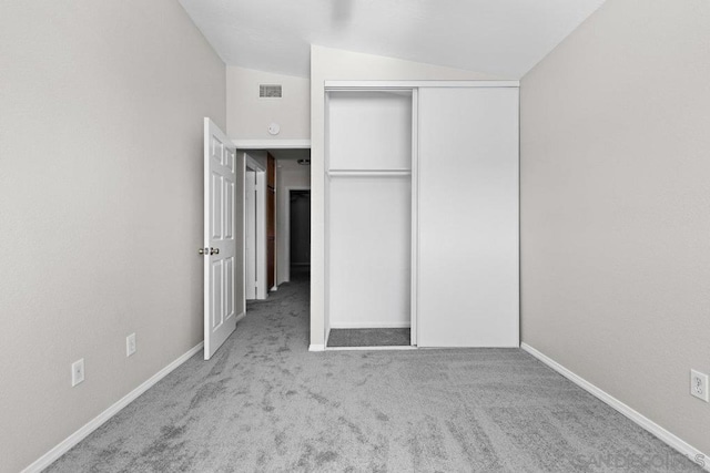 unfurnished bedroom featuring a closet, light colored carpet, and lofted ceiling