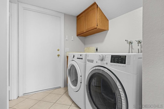 laundry room with washer and dryer, cabinets, and light tile patterned flooring