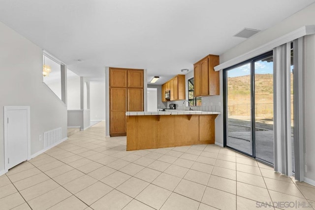 kitchen with tile countertops, light tile patterned flooring, and kitchen peninsula