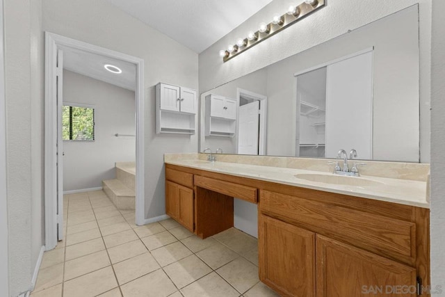 bathroom with tile patterned flooring, vanity, and vaulted ceiling