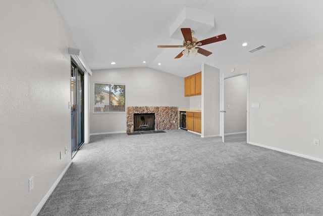 unfurnished living room with a stone fireplace, light colored carpet, ceiling fan, wine cooler, and lofted ceiling