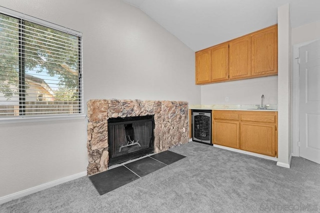 unfurnished living room featuring light colored carpet, beverage cooler, and vaulted ceiling