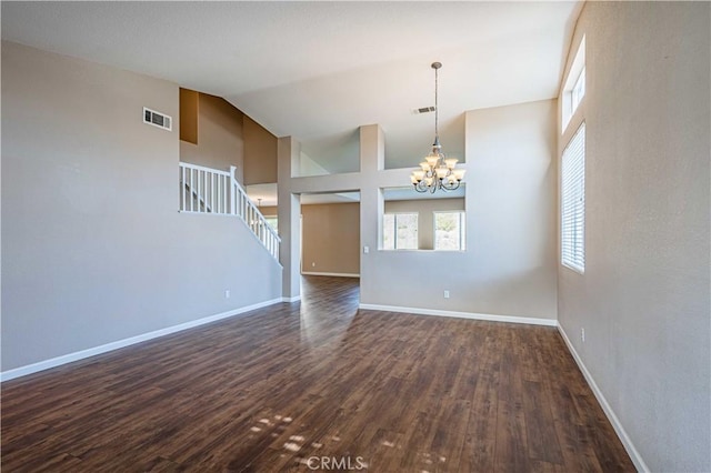 spare room with high vaulted ceiling, an inviting chandelier, and dark hardwood / wood-style flooring